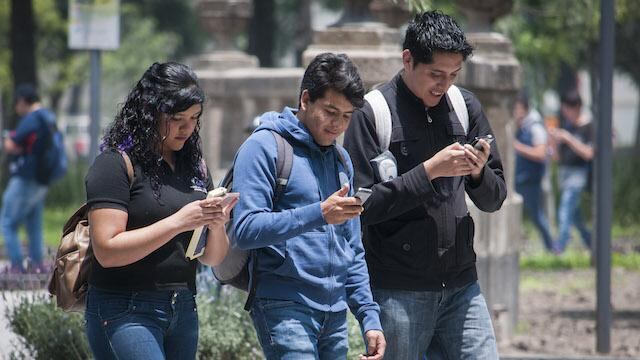 Unos jóvenes observan su teléfono celular.