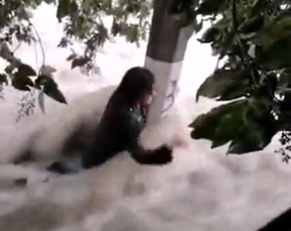 Joven se aferra a poste de luz para no ser arrastrado por corriente de agua