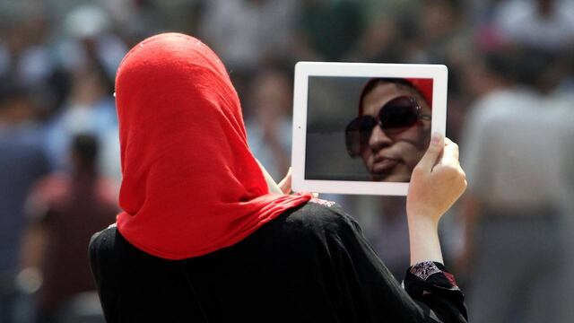 Una mujer egipcia que usa su tableta para protestar contra los manifestantes en la plaza Tahrir