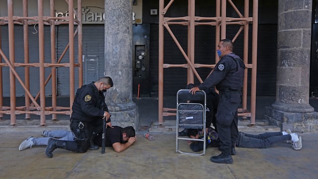 Policías someten a manifestantes.
