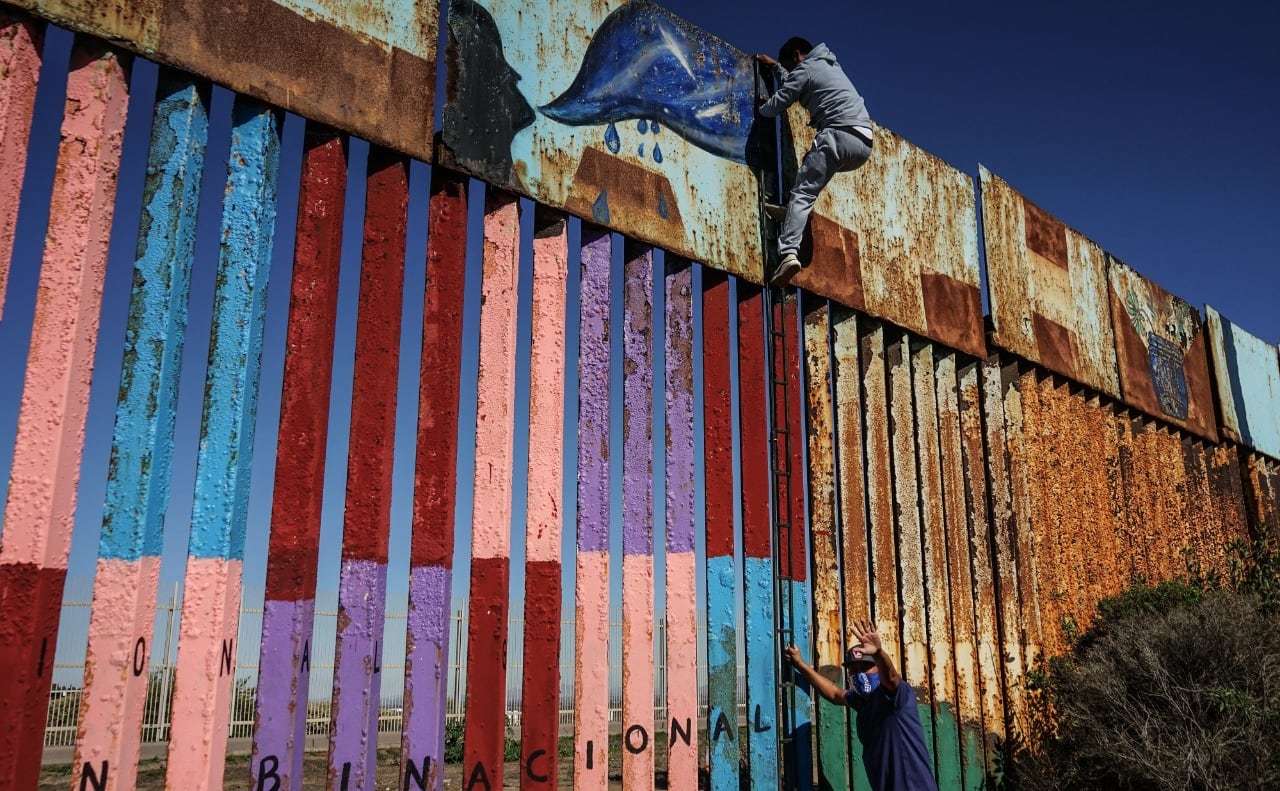 Migrantes intentando saltar muro con Estados Unidos