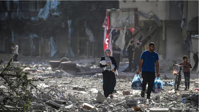 Palestinos caminan entre los escombros tras los ataques aéreos israelíes en el barrio de Tel al-Hawa, en la ciudad de Gaza