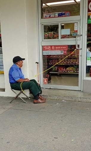 Hombre trabaja abriendo la puerta de un Oxxo