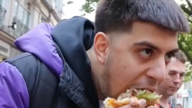 Influencer comiendo una hamburguesa frente a una protesta de veganos