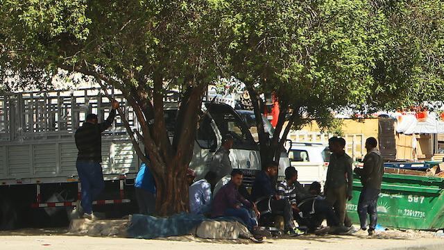 Trabajadores se resguardan del rayo del sol en la ciudad de Kuwait.