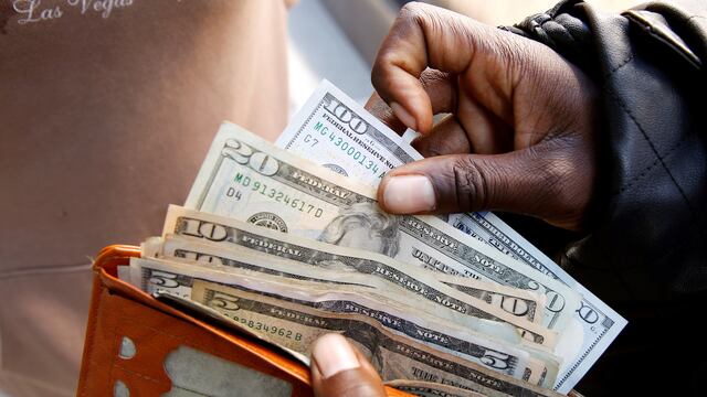 Un hombre guarda varios billetes estadounidenses en su cartera