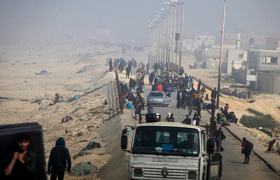 El polvo y el humo de los ataques aéreos envuelven a los palestinos que caminan por la carretera Al Rashid huyendo de los combates en el norte de la Franja de Gaza