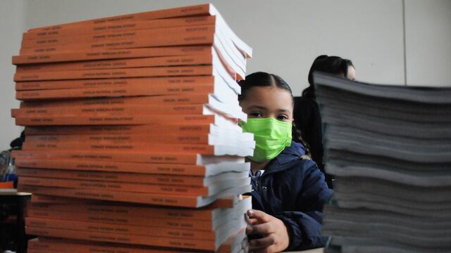 Una niña se asoma detrás de los nuevos libros de texto de la SEP