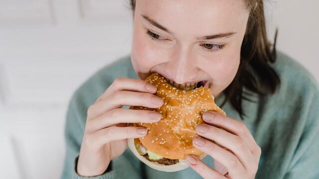 Mujer mordiendo hamburguesa.