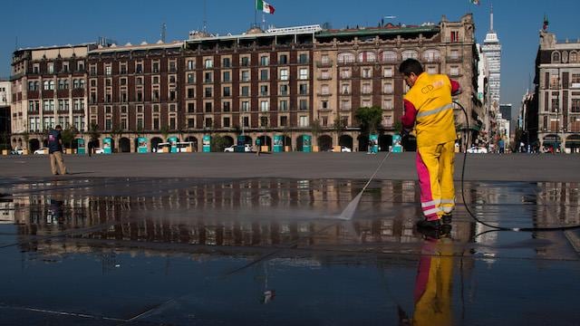 Un trabajador limpia el Zócalo de la Ciudad de México.