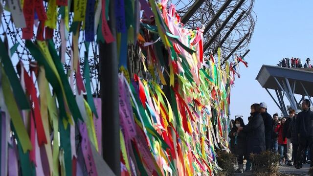 Personas miran listones con llamados a la paz y la reunificación de la península de Corea en la ciudad fronteriza de Paju.