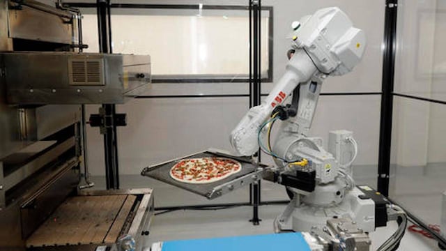 Un robot coloca una pizza en un horno a Zume Pizza.