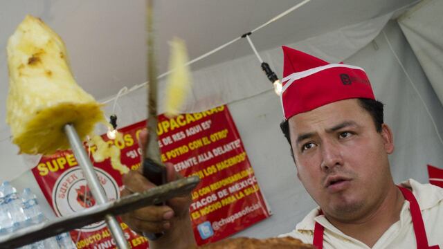 Taquero experto haciendo volar la piña al taco