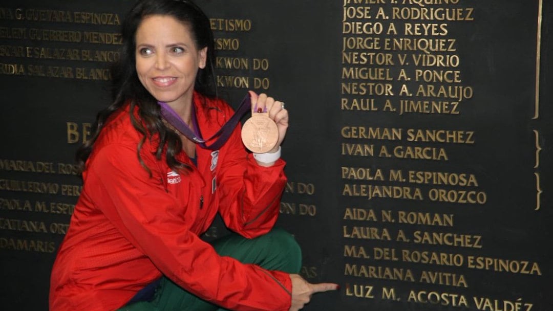 Luz Acosta posando junto al muro de atletas ganadores en JJOO