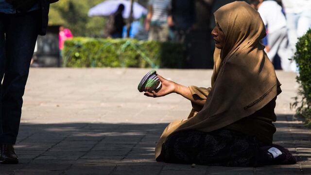 Una mujer pide monedas en el Bosque de Chapultepec.