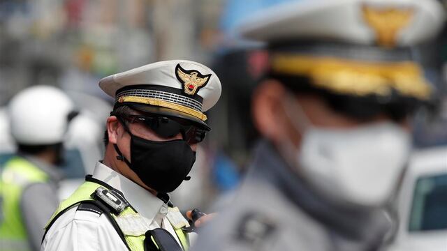 Dos policías sudcoreanos llevan a cabo sus labores portanda cubrebocas protectores.