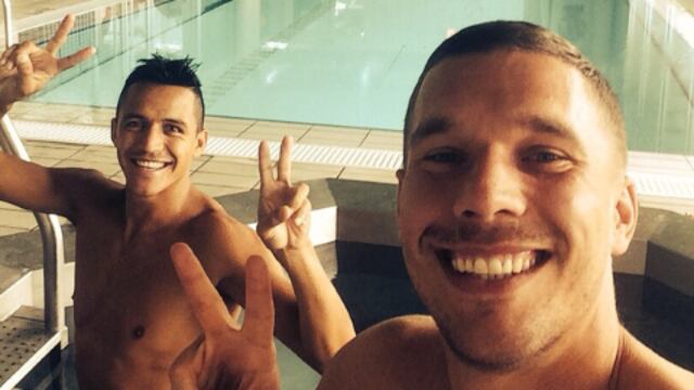 El campeón del mundo Lukas Podolski mira fotos eróticas durante mientras se encuentra en la banca