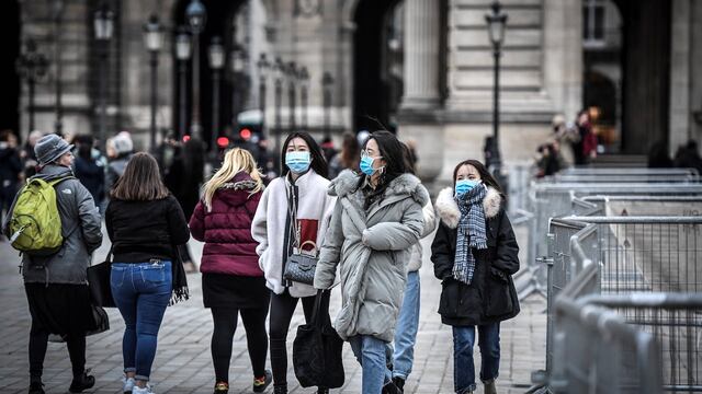 Tres mujeres cubren su boca mientras pasean por París