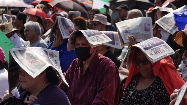 Cientos de personas se cubrieron del sol mientras esperaban la entrega del apoyo económico del programa social Ingreso Ciudadano Universal para mujeres y hombres de 57 a 59 años