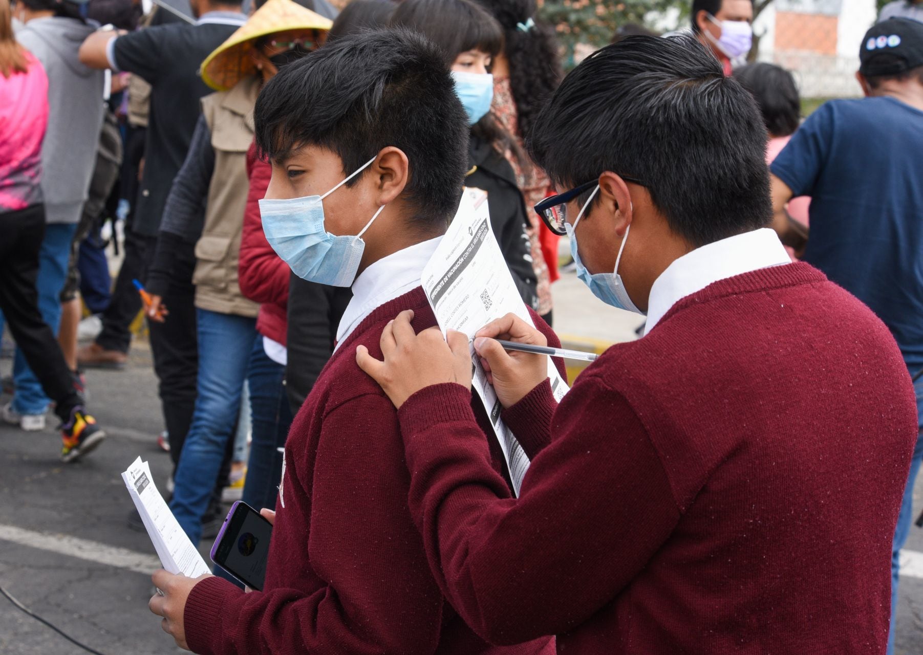 Menores de 12 y 13 años de edad llenando registro de vacunación contra Covid-19.