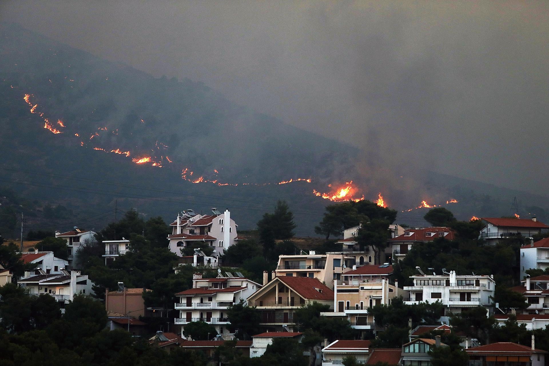 Un incendio se acerca a las casas en el monte Penteli, en el noreste de Grecia, este lunes. EFE/ George Vitsaras