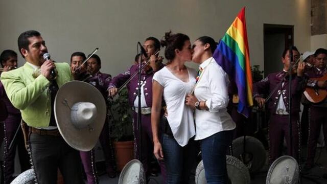 Pareja del mismo sexo con mariachis de fondo