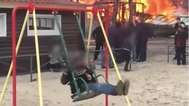 Niño juega mientras una casa se incendia a sus espaldas.